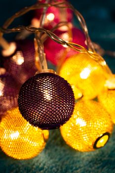 Battery garland with metallic grid balls on blue blanket. Closeup view with blurred background.