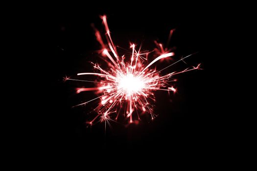Low light photo of bengali fire isolated on black background with red toning. A lot of light and sparks. Underexposed photo.