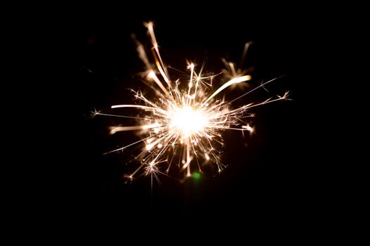 Low light photo of bengali fire isolated on black background. A lot of light and sparks. Underexposed photo.