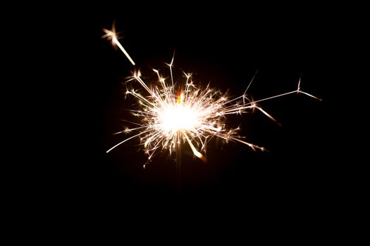 Low light photo of bengali fire isolated on black background. A lot of light and sparks. Underexposed photo.