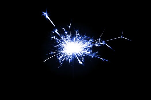 Low light photo of bengali fire isolated on black background with blue toning. A lot of light and sparks. Underexposed photo.