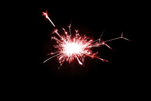 Low light photo of bengali fire isolated on black background with red toning. A lot of light and sparks. Underexposed photo.