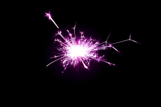 Low light photo of bengali fire isolated on black background with purple toning. A lot of light and sparks. Underexposed photo.