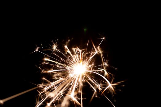 Low light photo of bengali fire isolated on black background. A lot of light and sparks. Underexposed photo.