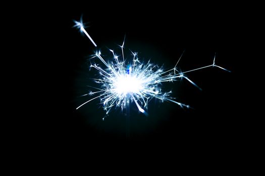 Low light photo of bengali fire isolated on black background with blue toning. A lot of light and sparks. Underexposed photo.