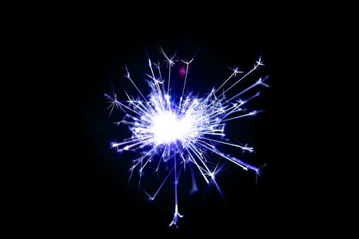 Low light photo of bengali fire isolated on black background with blue toning. A lot of light and sparks. Underexposed photo.
