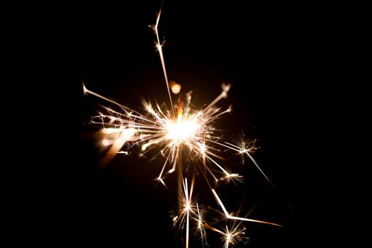 Low light photo of bengali fire isolated on black background. A lot of light and sparks. Underexposed photo.