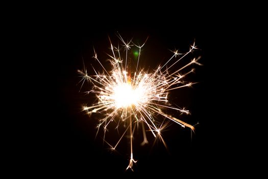 Low light photo of bengali fire isolated on black background. A lot of light and sparks. Underexposed photo.