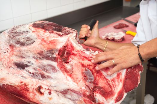 butcher cutting meat in the butchery. Close up