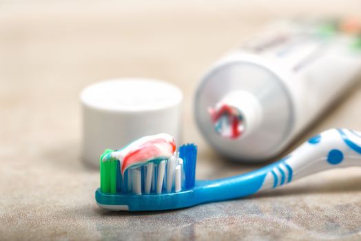 Toothbrush in the foreground and toothpaste on the shelf