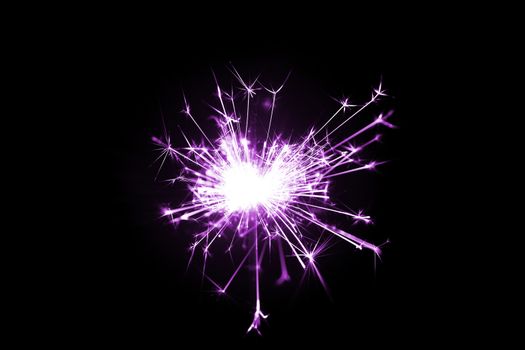 Low light photo of bengali fire isolated on black background with purple toning. A lot of light and sparks. Underexposed photo.