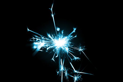 Low light photo of bengali fire isolated on black background with blue toning. A lot of light and sparks. Underexposed photo.