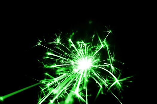 Low light photo of bengali fire isolated on black background with green toning. A lot of light and sparks. Underexposed photo.