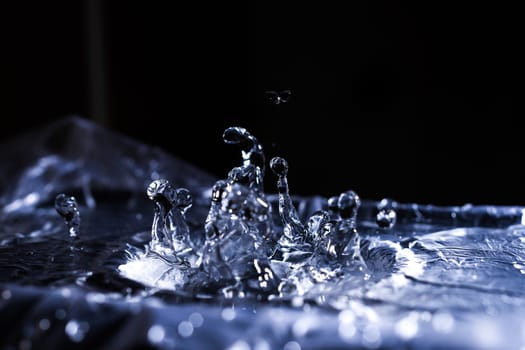 Water drops splashing on acoustic membrane. A lot of drops in air. High frequency of sound waves. Water cloud small drops. Frozen time shot.