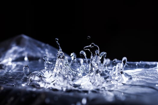 Water drops splashing on acoustic membrane. A lot of drops in air. High frequency of sound waves. Water cloud small drops. Frozen time shot.