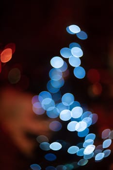 Outdoor Christmas tree defocused light. White lights in tree is blurred. Big beautiful curly bokeh