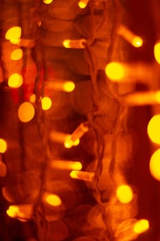 Vertical Christmas garland wall on glass window. Light is orange and defocused. Blurred background, new year mood.
