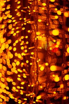 Vertical Christmas garland wall on glass window. Light is orange and defocused. Blurred background, new year mood.