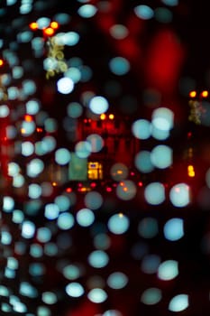 Vertical Christmas garland wall on glass window. Light is white and defocused. Blurred background, new year mood.