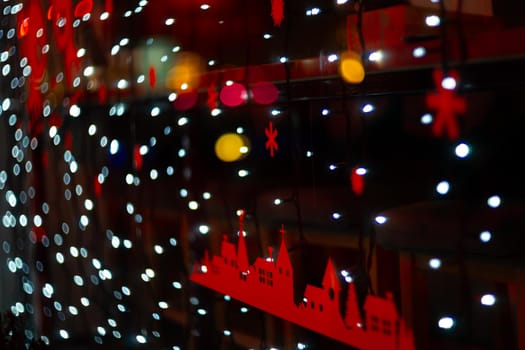 Vertical Christmas garland wall on glass window. Light is white and defocused. Blurred background, new year mood.