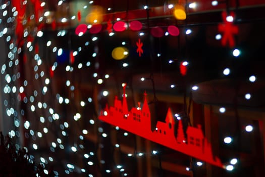 Vertical Christmas garland wall on glass window. Light is white and defocused. Blurred background, new year mood.