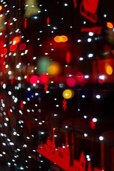 Vertical Christmas garland wall on glass window. Light is white and defocused. Blurred background, new year mood.