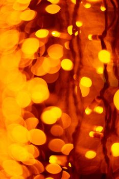 Vertical Christmas garland wall on glass window. Light is orange and defocused. Blurred background, new year mood.