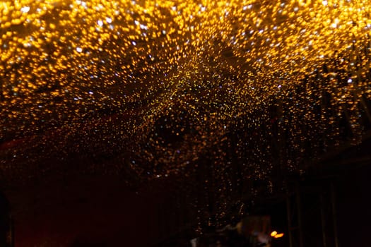 Horizontal Christmas garland wall on glass roof Light is orange and defocused. Blurred background, new year mood. Underexposed low light photo