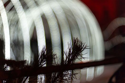 Christmas tree in focus in foreground. Christmas garland on blurred background. Light is light and defocused. Blurred background, new year mood.