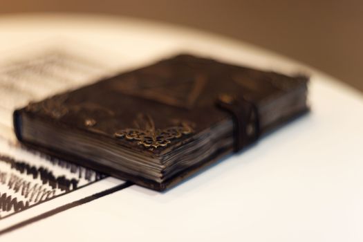 Handmade magic notebook with tower symbol on cover. Leather cover and handmade sheets inside. Very blurred background with soft focus on notebook.