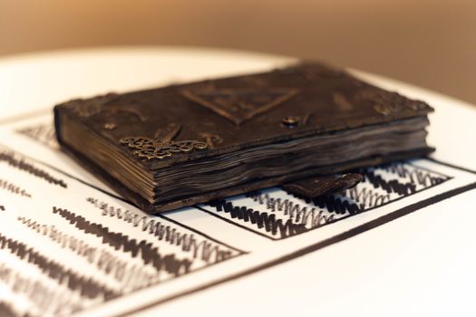 Handmade magic notebook with tower symbol on cover. Leather cover and handmade sheets inside. Very blurred background with soft focus on notebook.