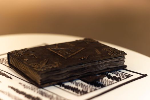 Handmade magic notebook with tower symbol on cover. Leather cover and handmade sheets inside. Very blurred background with soft focus on notebook.