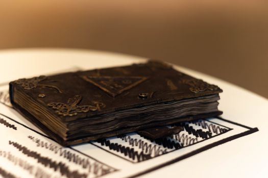 Handmade magic notebook with tower symbol on cover. Leather cover and handmade sheets inside. Very blurred background with soft focus on notebook.