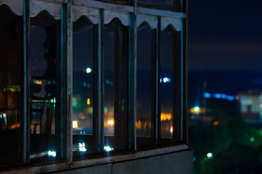 Long exposure cityscape night photo. Balcony with windows let through the lights of the night city.