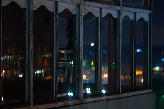 Long exposure cityscape night photo. Balcony with windows let through the lights of the night city.