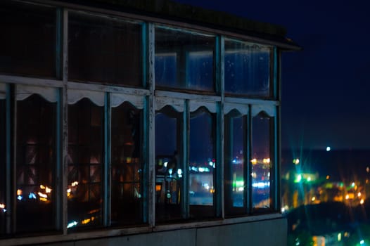 Long exposure cityscape night photo. Balcony with windows let through the lights of the night city.