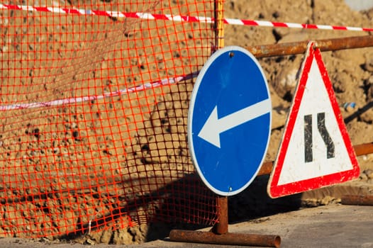 Road atention signs near the trench on the road. Repair work is underway.