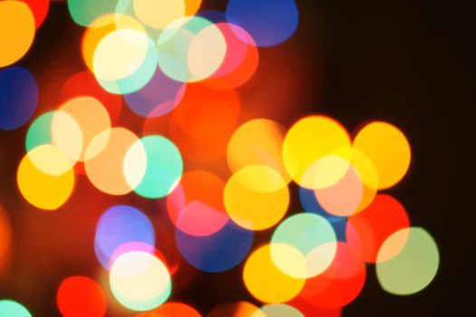 Multi-color holiday garland. Garland is blurred. Many colorful round lights. Fully defocused photo. Blurred background and foreground. Holiday mood. New Year and Christmas is coming.