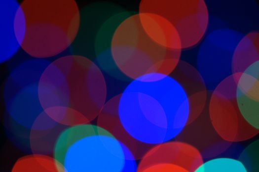 Multi-color blue holiday garland. Garland is blurred. Many very big colorful round lights. Fully defocused photo. Blurred background and foreground. Holiday mood. New Year and Christmas is coming.