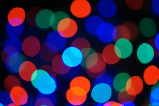 Multi-color blue holiday garland. Garland is blurred. Many big colorful round lights. Fully defocused photo. Blurred background and foreground. Holiday mood. New Year and Christmas is coming.