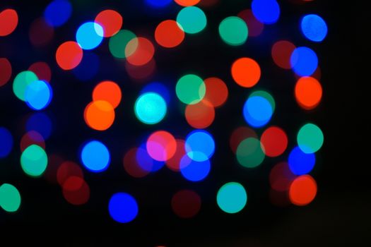 Multi-color blue holiday garland. Garland is blurred. Many big colorful round lights. Fully defocused photo. Blurred background and foreground. Holiday mood. New Year and Christmas is coming.