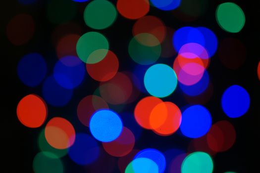 Multi-color blue holiday garland. Garland is blurred. Many big colorful round lights. Fully defocused photo. Blurred background and foreground. Holiday mood. New Year and Christmas is coming.