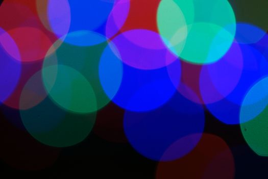 Multi-color blue holiday garland. Garland is blurred. Many very big colorful round lights. Fully defocused photo. Blurred background and foreground. Holiday mood. New Year and Christmas is coming.