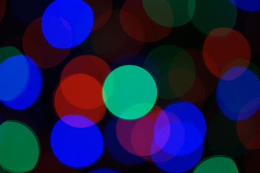 Multi-color blue holiday garland. Garland is blurred. Many very big colorful round lights. Fully defocused photo. Blurred background and foreground. Holiday mood. New Year and Christmas is coming.