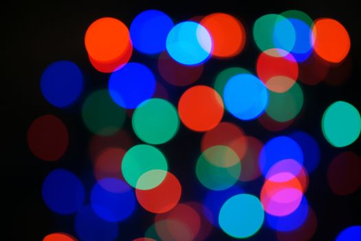 Multi-color blue holiday garland. Garland is blurred. Many big colorful round lights. Fully defocused photo. Blurred background and foreground. Holiday mood. New Year and Christmas is coming.