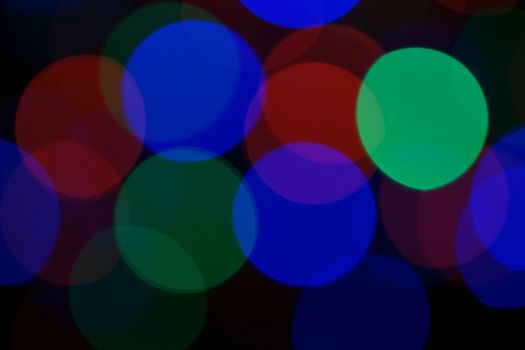 Multi-color blue holiday garland. Garland is blurred. Many very big colorful round lights. Fully defocused photo. Blurred background and foreground. Holiday mood. New Year and Christmas is coming.