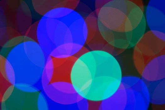 Multi-color blue holiday garland. Garland is blurred. Many very big colorful round lights. Fully defocused photo. Blurred background and foreground. Holiday mood. New Year and Christmas is coming.