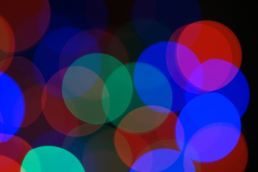 Multi-color blue holiday garland. Garland is blurred. Many very big colorful round lights. Fully defocused photo. Blurred background and foreground. Holiday mood. New Year and Christmas is coming.