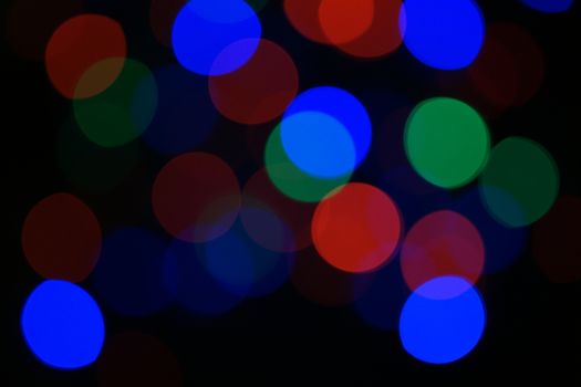 Multi-color blue holiday garland. Garland is blurred. Many big colorful round lights. Fully defocused photo. Blurred background and foreground. Holiday mood. New Year and Christmas is coming.