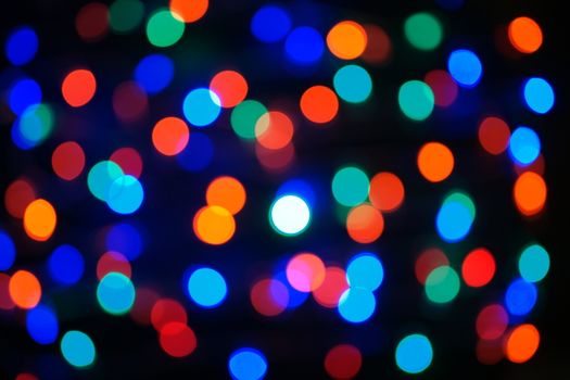Multi-color blue holiday garland. Garland is blurred. Many big colorful round lights. Fully defocused photo. Blurred background and foreground. Holiday mood. New Year and Christmas is coming.